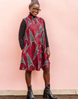 The model is wearing red and black dress with navy blue and beige print