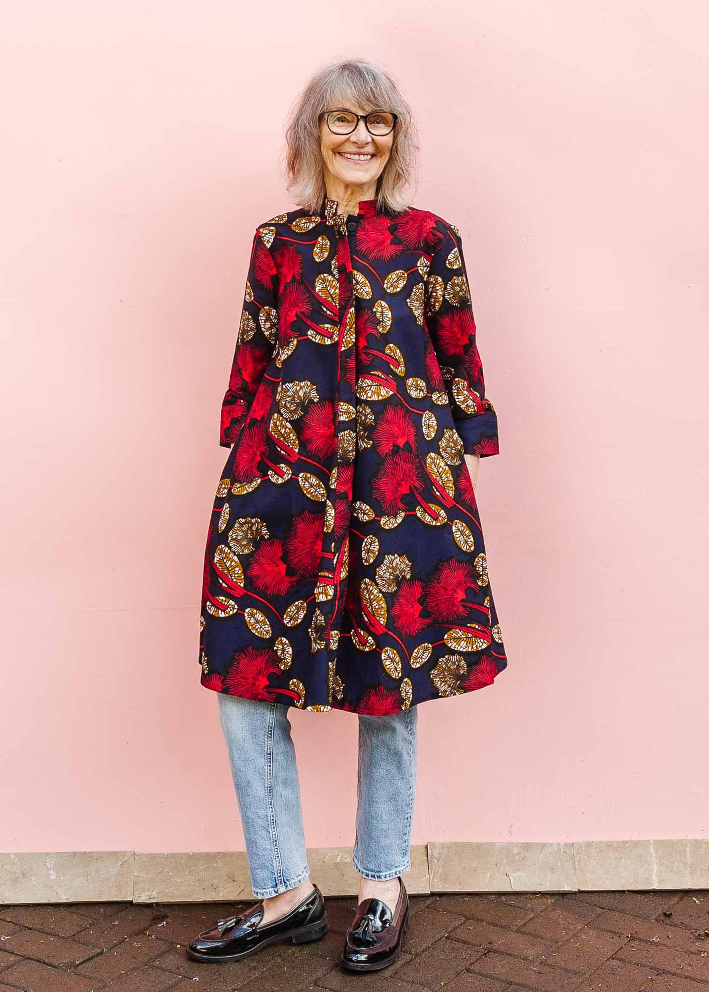 The model is wearing navy dress with red, white and orange floral print