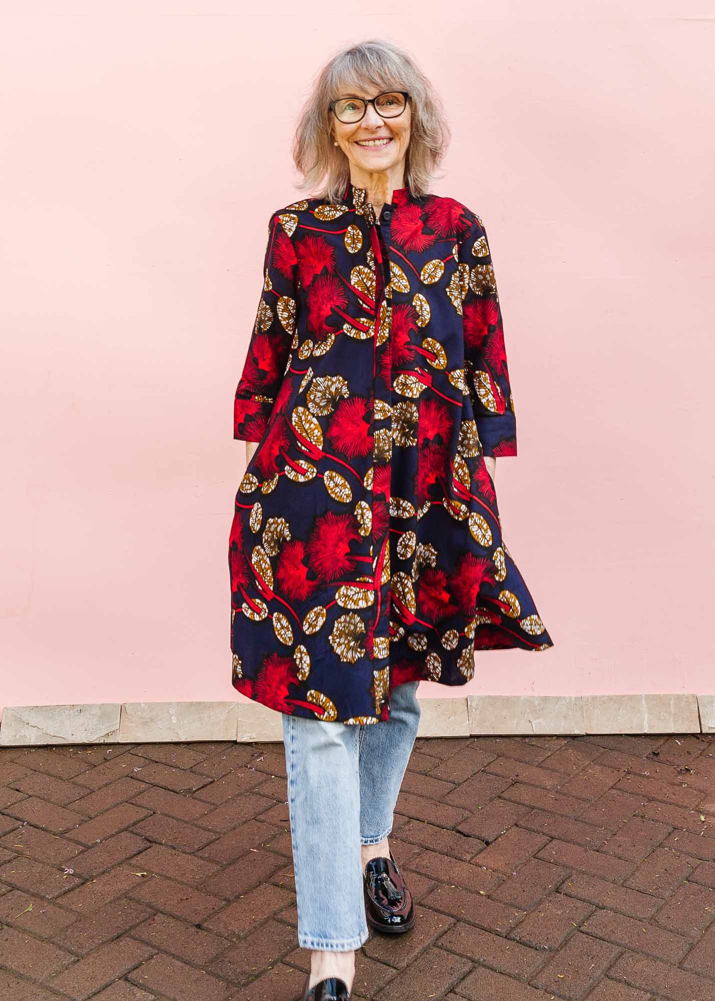 The model is wearing navy dress with red, white and orange floral print