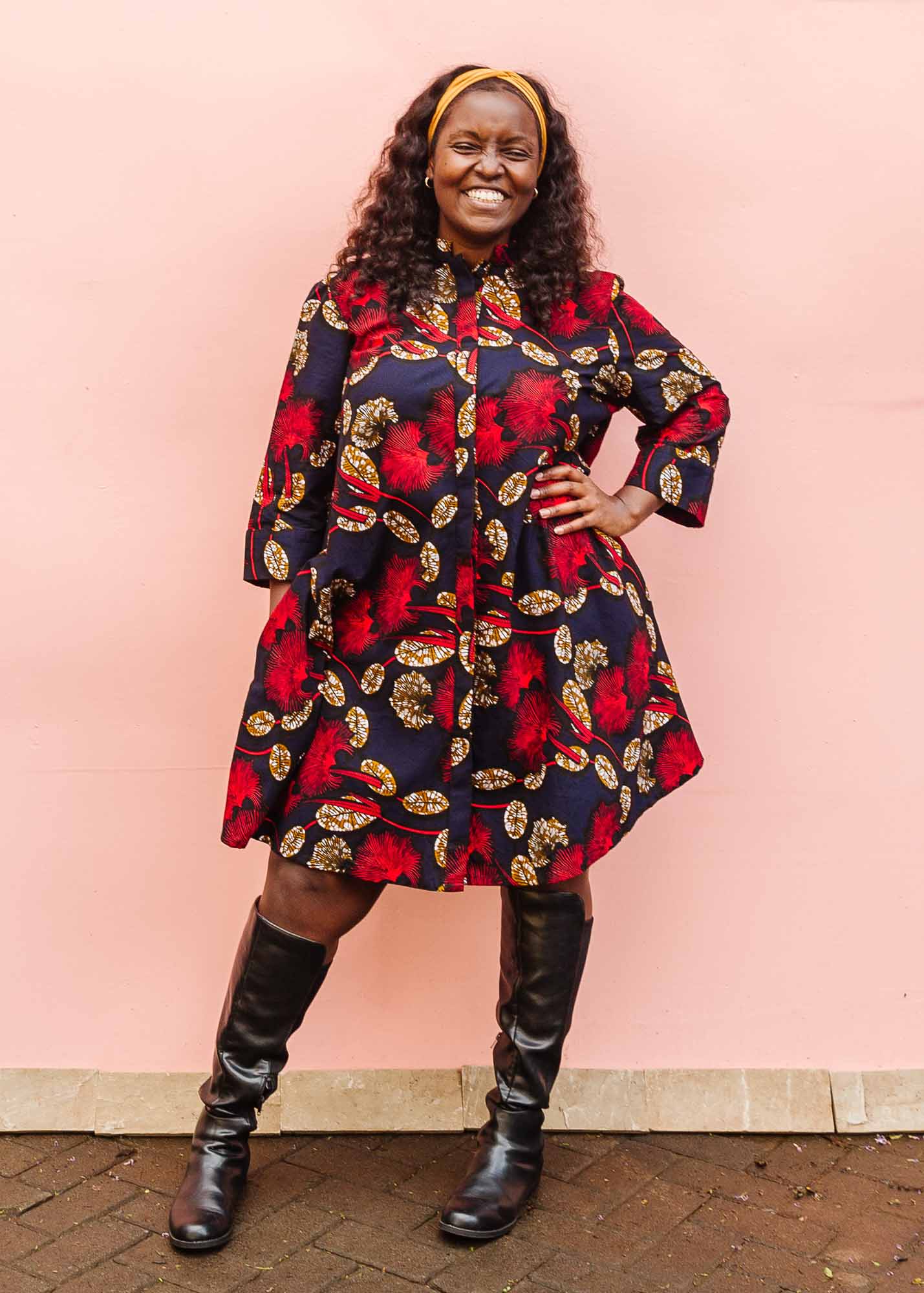The model is wearing navy dress with red, white and orange floral print