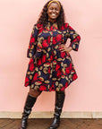 The model is wearing navy dress with red, white and orange floral print