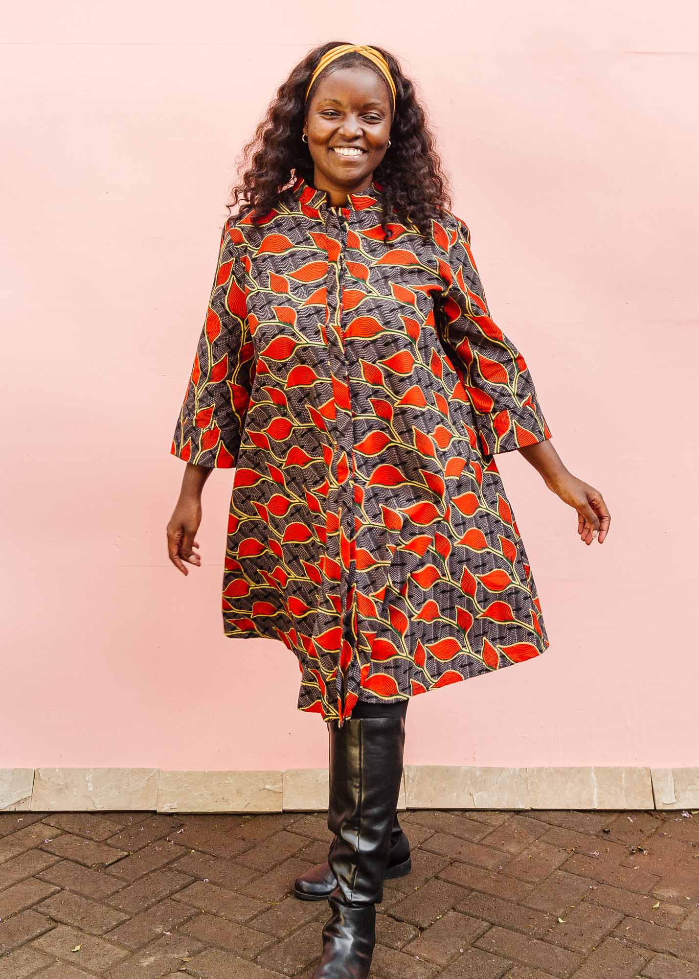 The model is wearing grey dress with red, yellow and black leaf print
