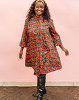 The model is wearing grey dress with red, yellow and black leaf print