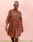 The model is wearing grey dress with red, yellow and black leaf print