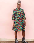 The model is wearing multicolored leaf print dress
