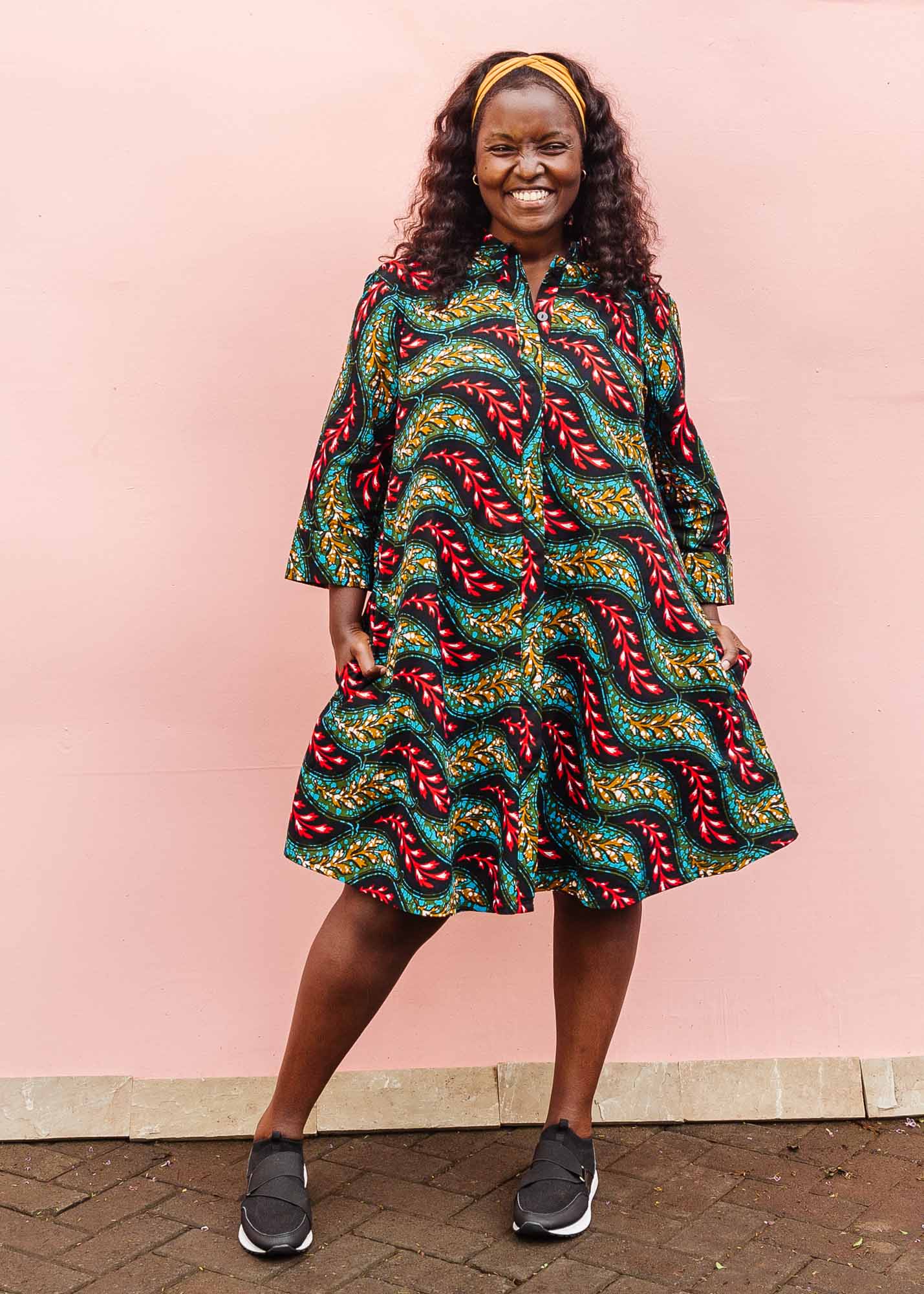 The model is wearing multicolored leaf print dress