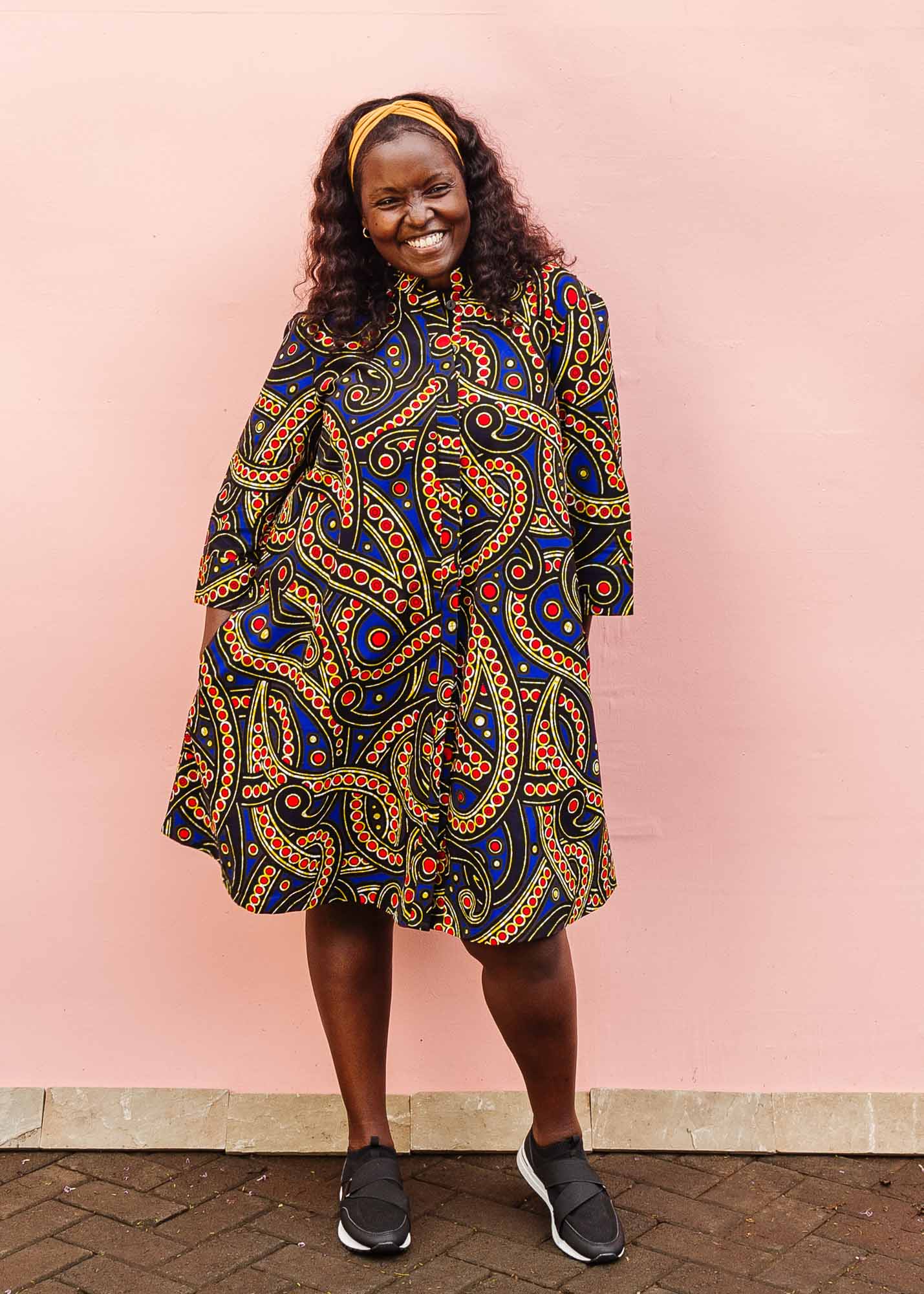 The model is wearing blue, red, black, yellow and white ornamental print dress