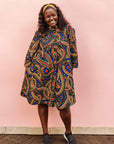 The model is wearing blue, red, black, yellow and white ornamental print dress