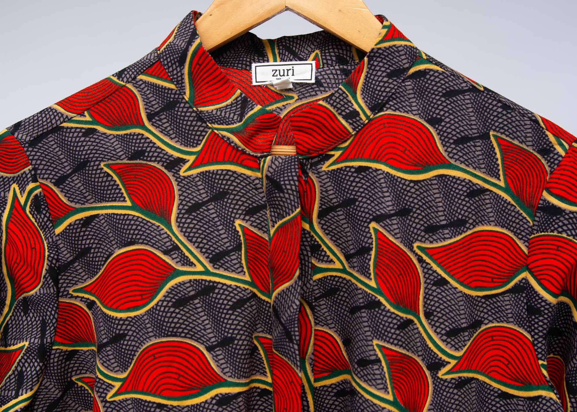 Display of grey dress with red, yellow and black leaf print
