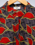 Display of grey dress with red, yellow and black leaf print