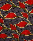 Close up display of grey dress with red, yellow and black leaf print, fabric