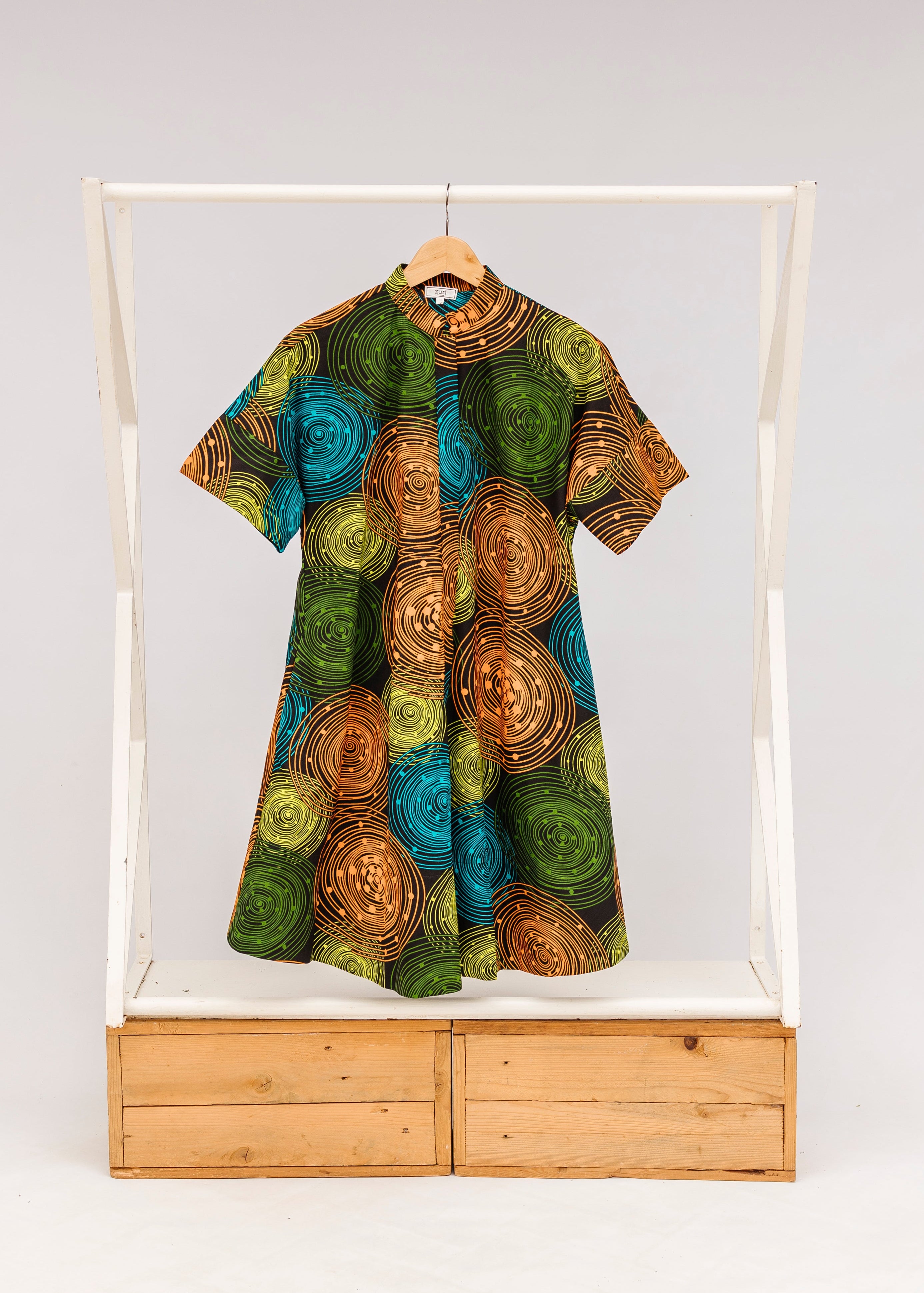 Display of black dress with orange, yellow, blue and green swirls, fabric.