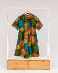 Display of black dress with orange, yellow, blue and green swirls, fabric.