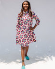 Model wearing white dress with yellow, red and blue bug print.