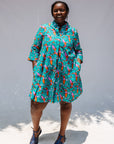 Model wearing teal dress with pink and orange shrimp print.