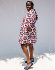 Model wearing white dress with yellow, red and blue bug print.