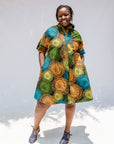 Model wearing black dress with orange, yellow, blue and green swirls.