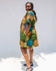 Model wearing black dress with orange, yellow, blue and green swirls.