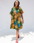 Model wearing black dress with orange, yellow, blue and green swirls.