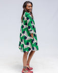 Model wearing green, black and white abstract print dress.
