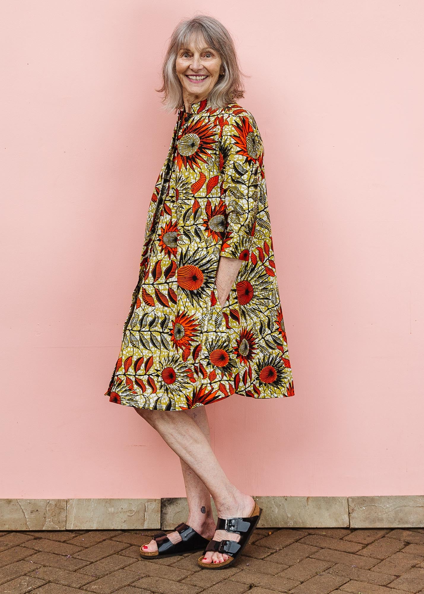 The model is wearing white and chartreuse dress with orange and black sunflowers