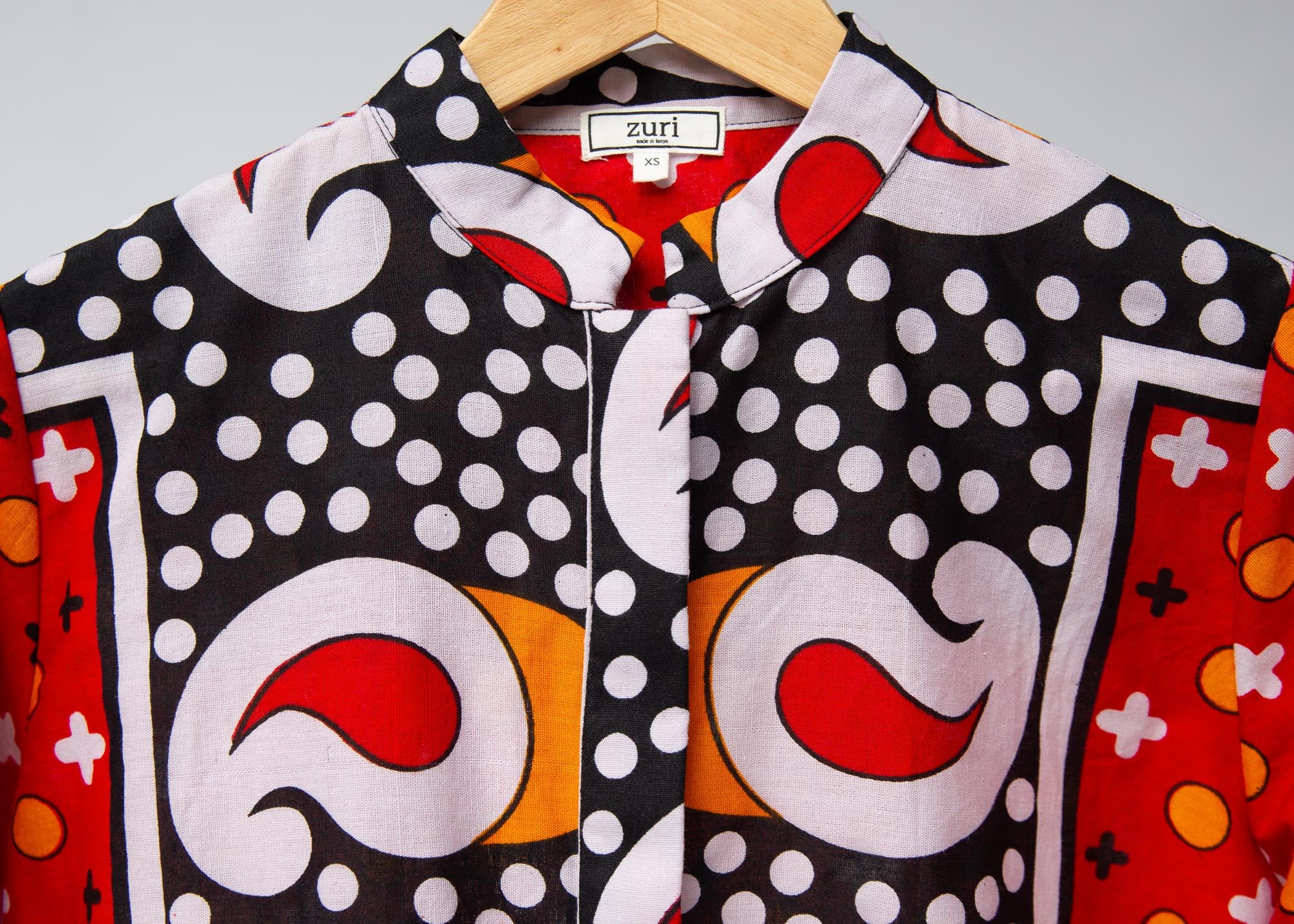 Display of red, white, black and orange mixed pattern long sleeved kanga shirt