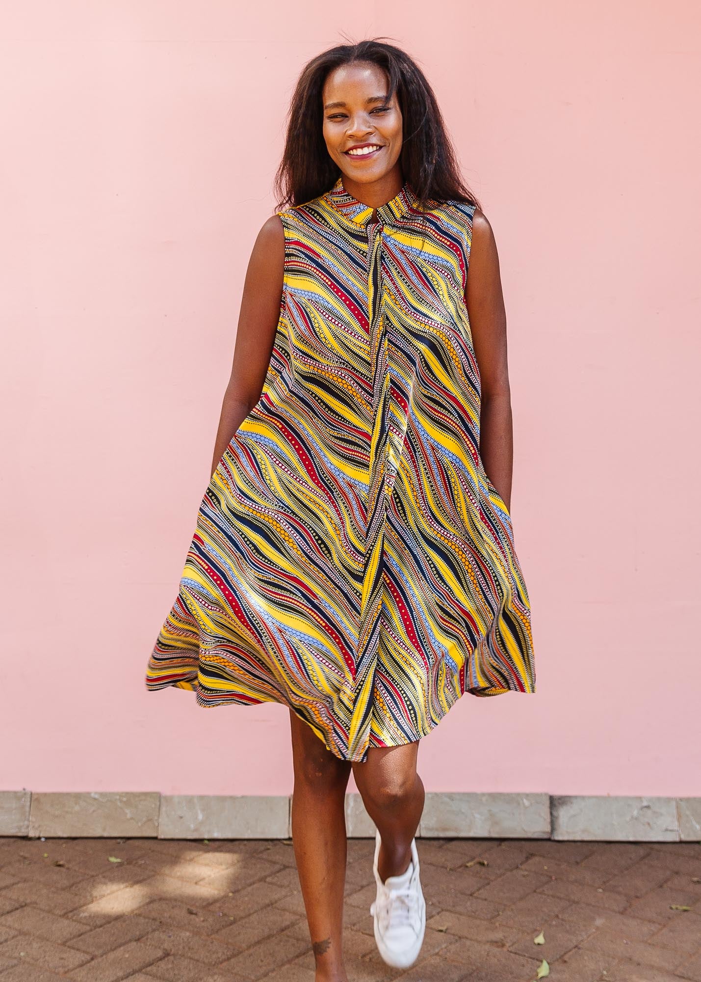 The model is wearing multi-colored abstract print dress