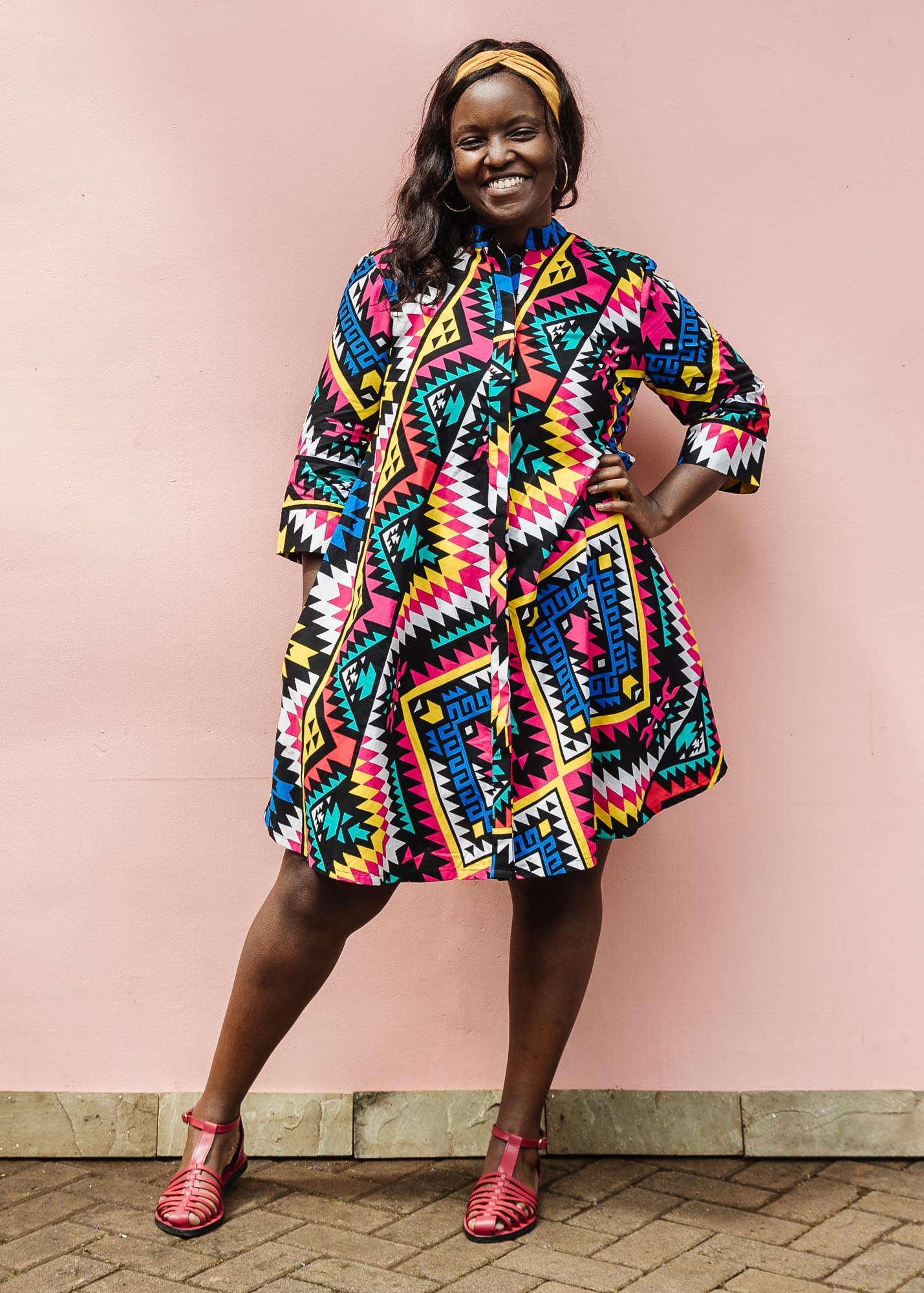 The model is wearing multi colored geometric print dress