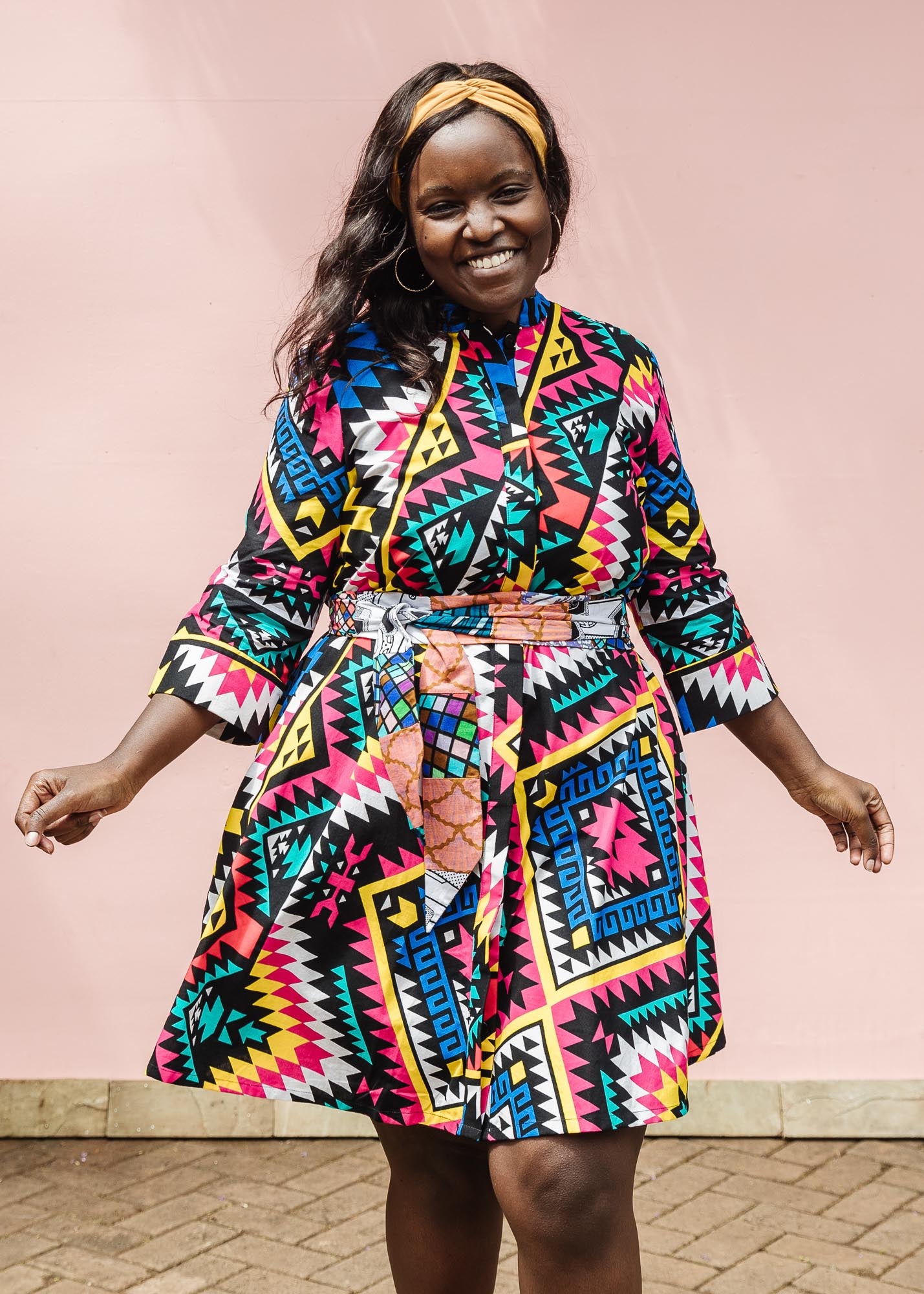 The model is wearing multi colored geometric print dress