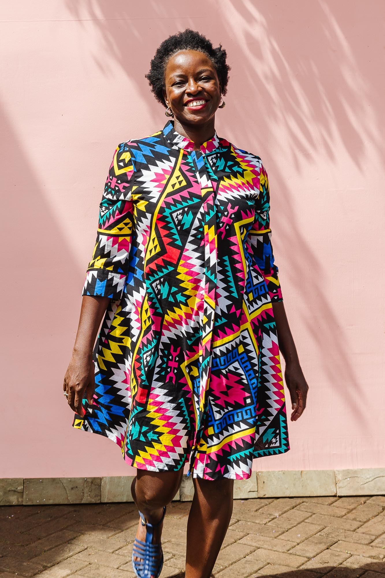 The model is wearing multi colored geometric print dress