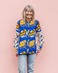 The model is wearing white, blue, black and orange mixed pattern long sleeved kanga shirt
