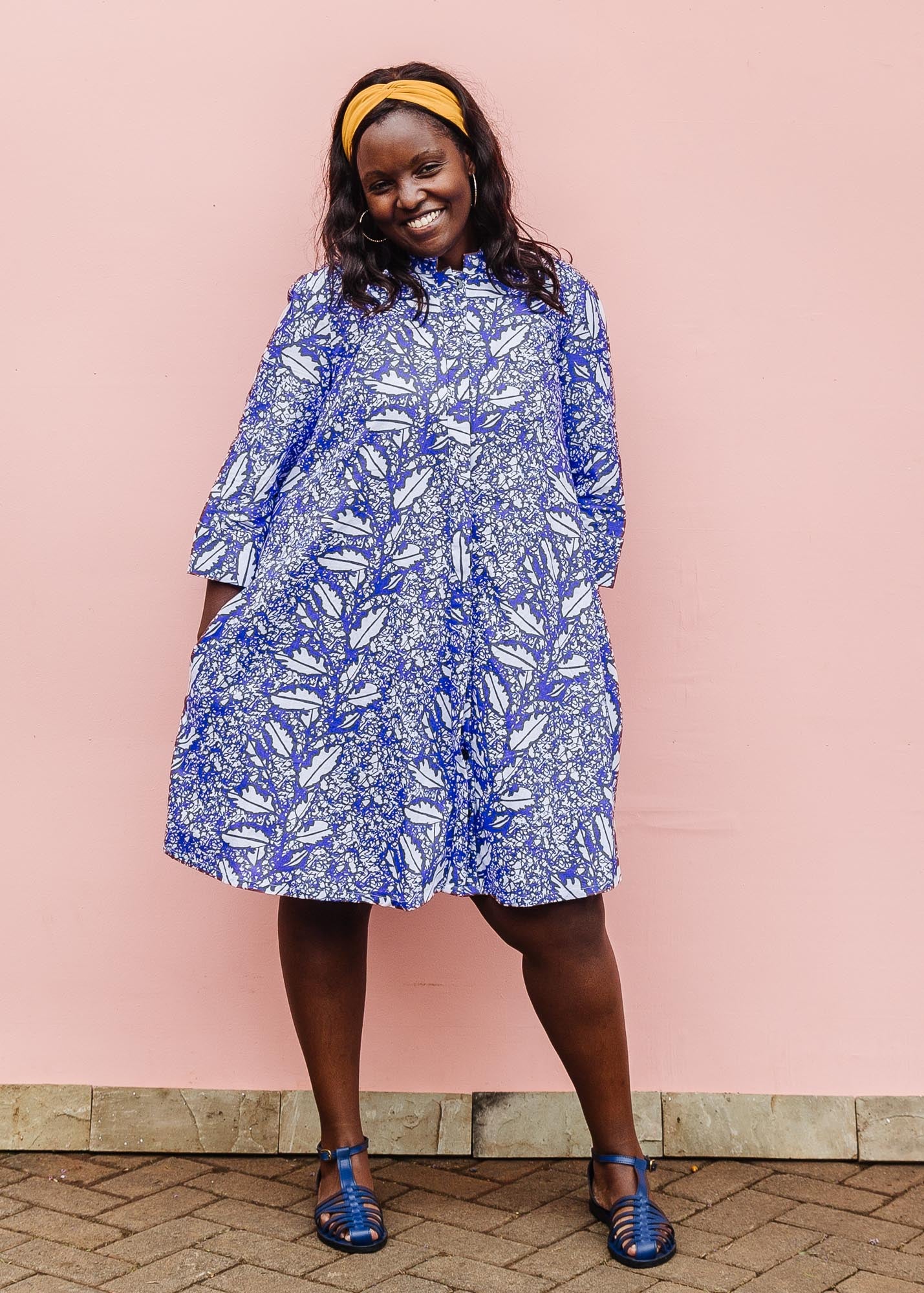 The model is wearing violet and white leaf print dress