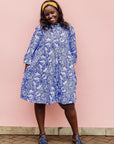 The model is wearing violet and white leaf print dress