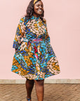 The model is wearing black dress with yellow dots and brown, blues, peach leaves.