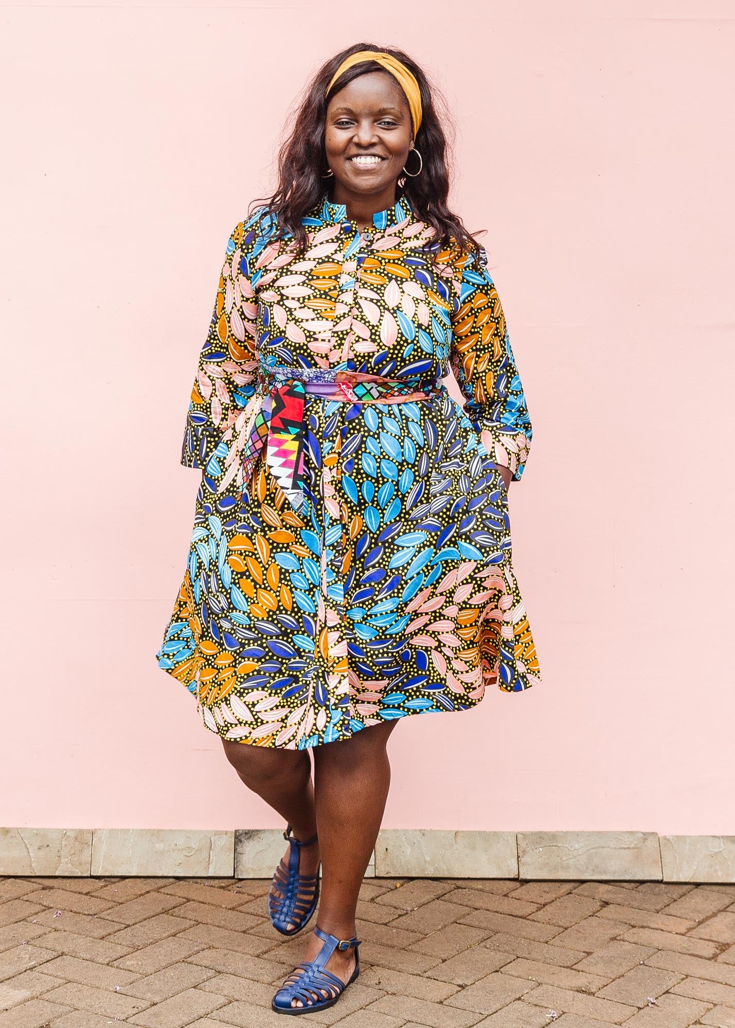 The model is wearing black dress with yellow dots and brown, blues, peach leaves.