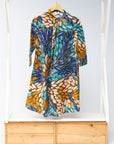 Display of black dress with yellow dots and brown, blues, peach leaves.