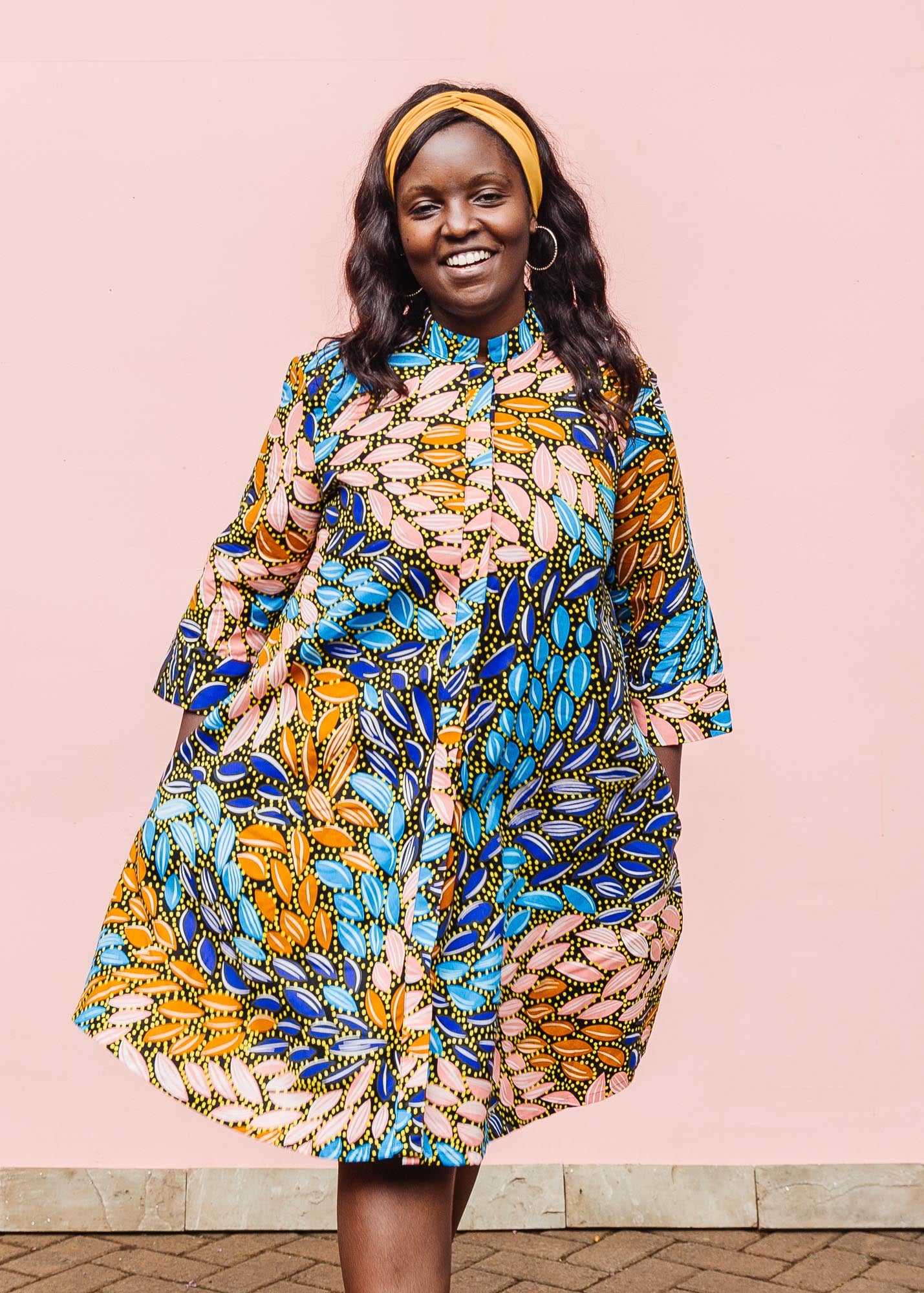 The model is wearing black dress with yellow dots and brown, blues, peach leaves.