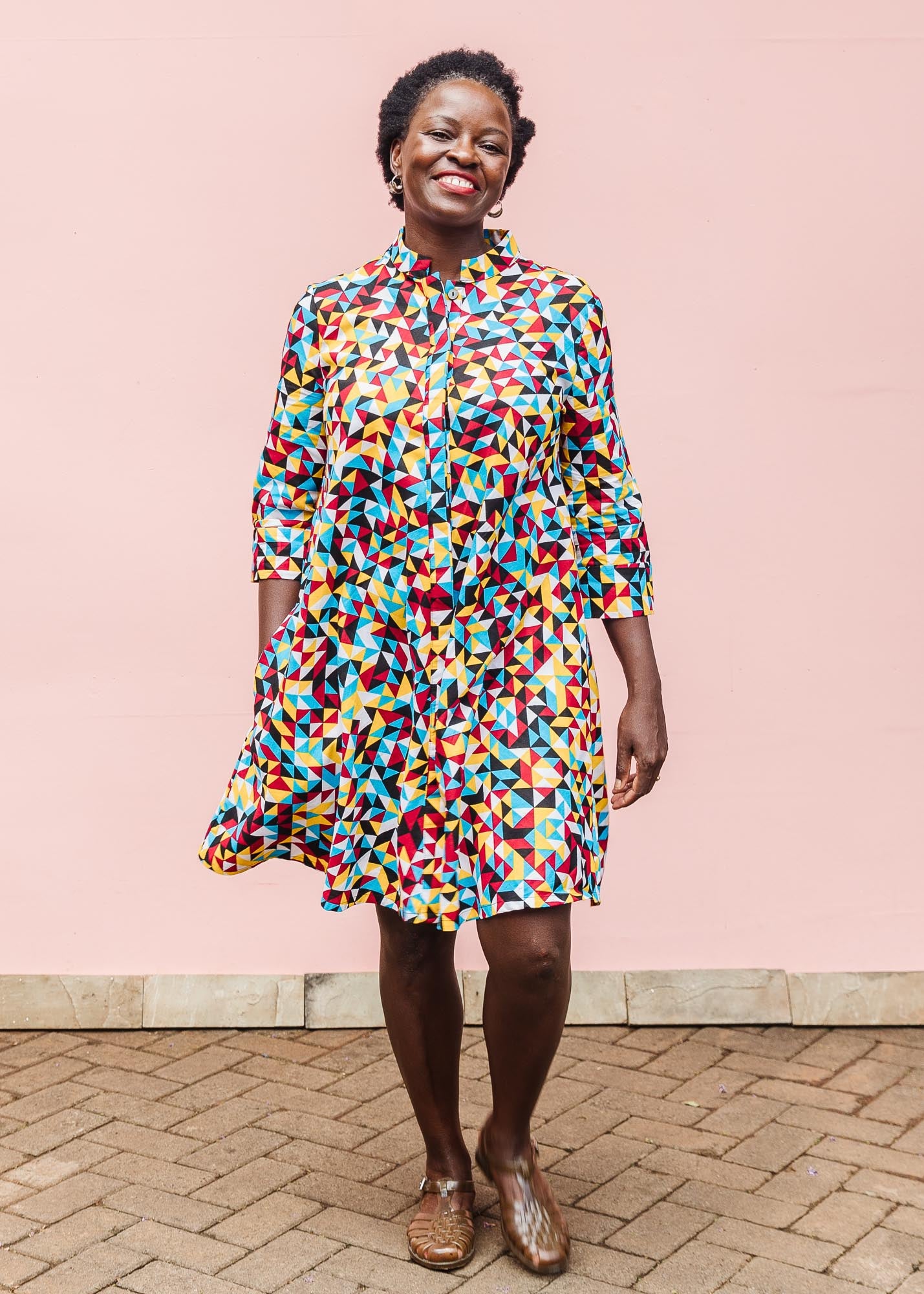 The model is wearing multi colored geometric print dress