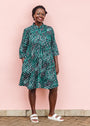 The model is wearing black, green and white geometric print dress
