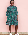 The model is wearing black, green and white geometric print dress