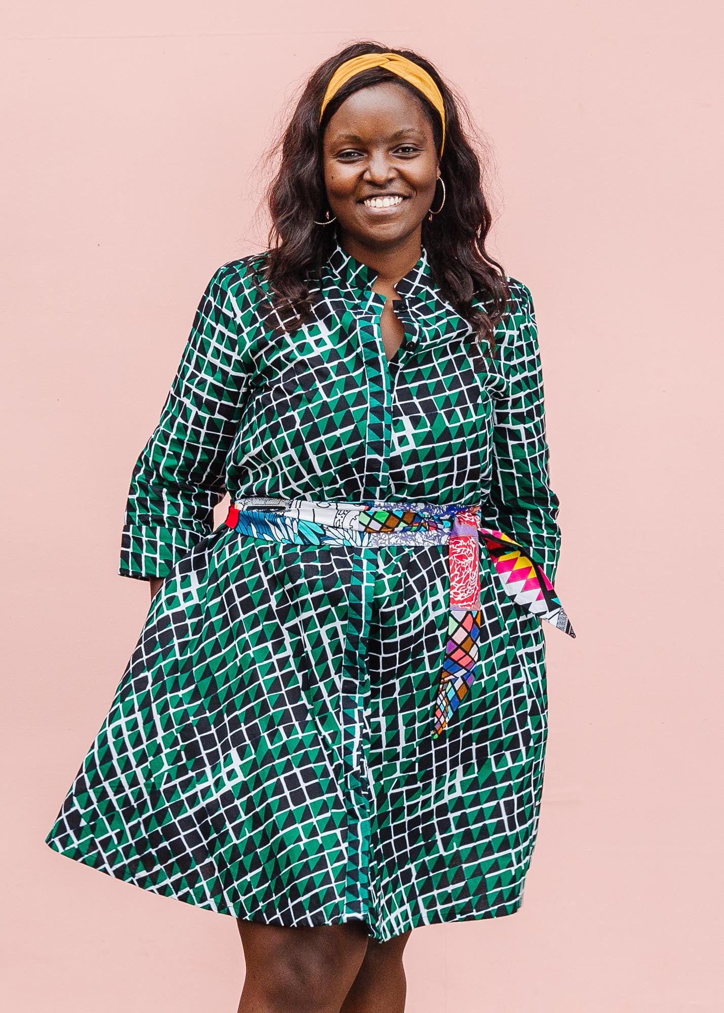 The model is wearing black, green and white geometric print dress
