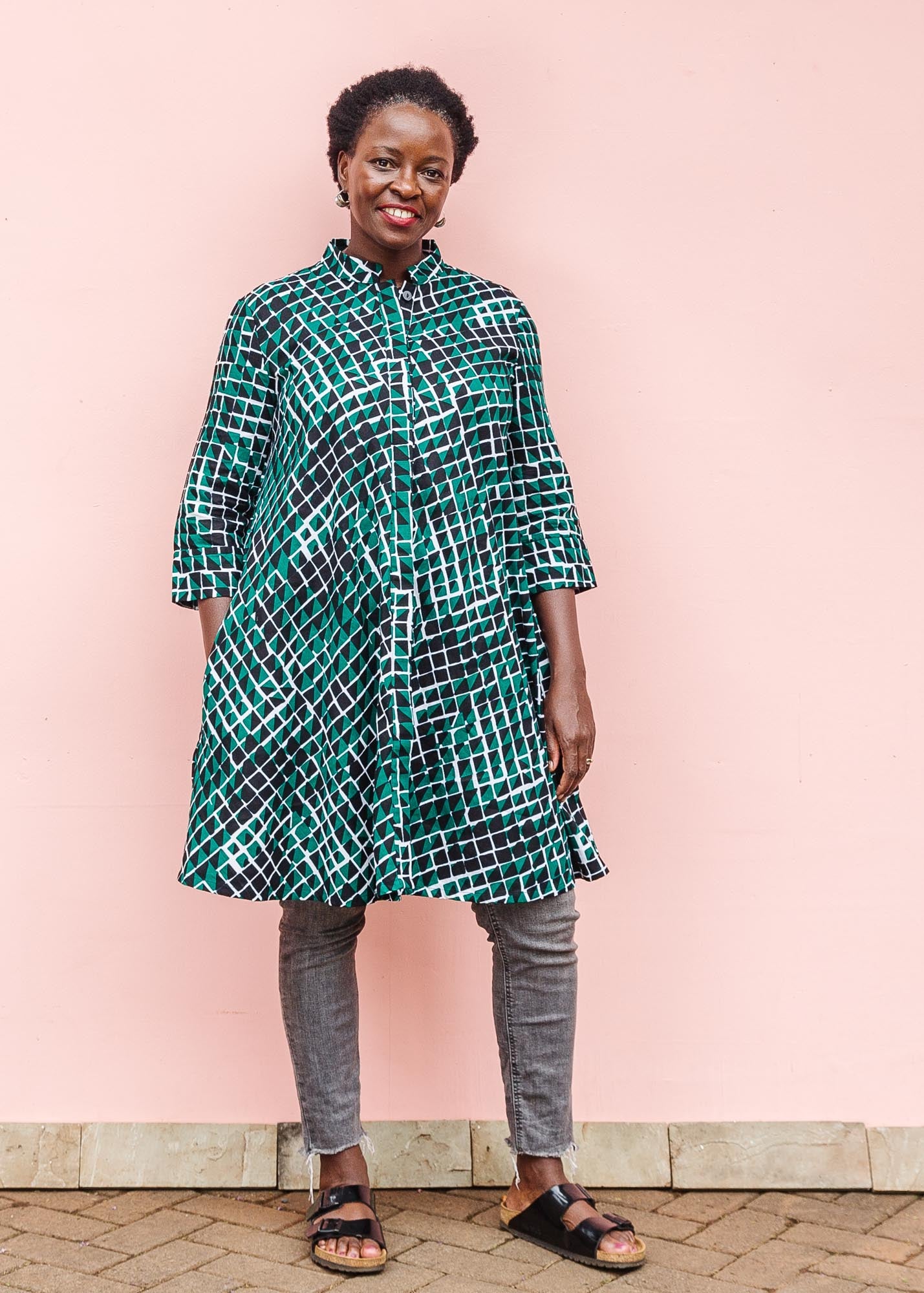 The model is wearing black, green and white geometric print dress