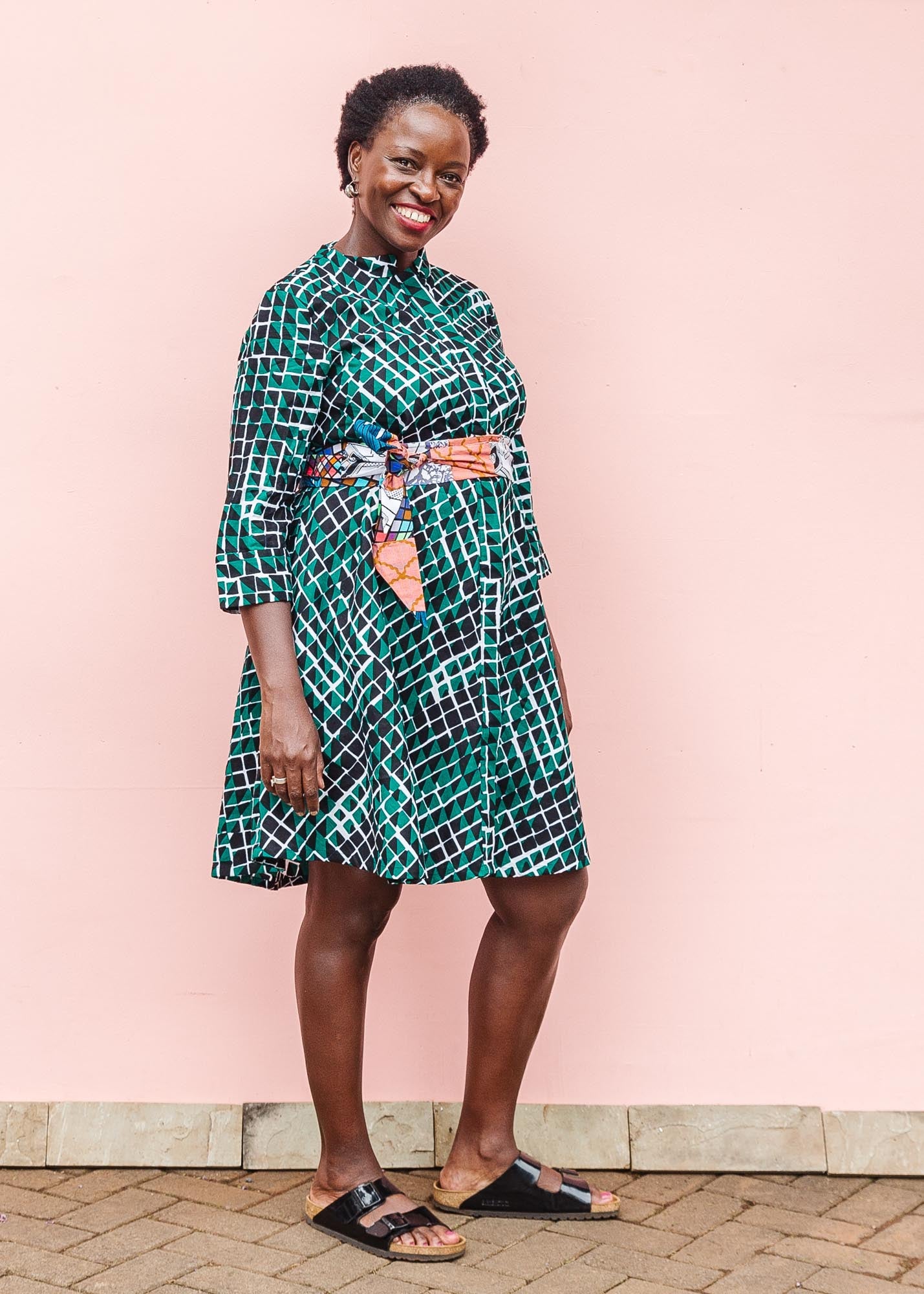 The model is wearing black, green and white geometric print dress