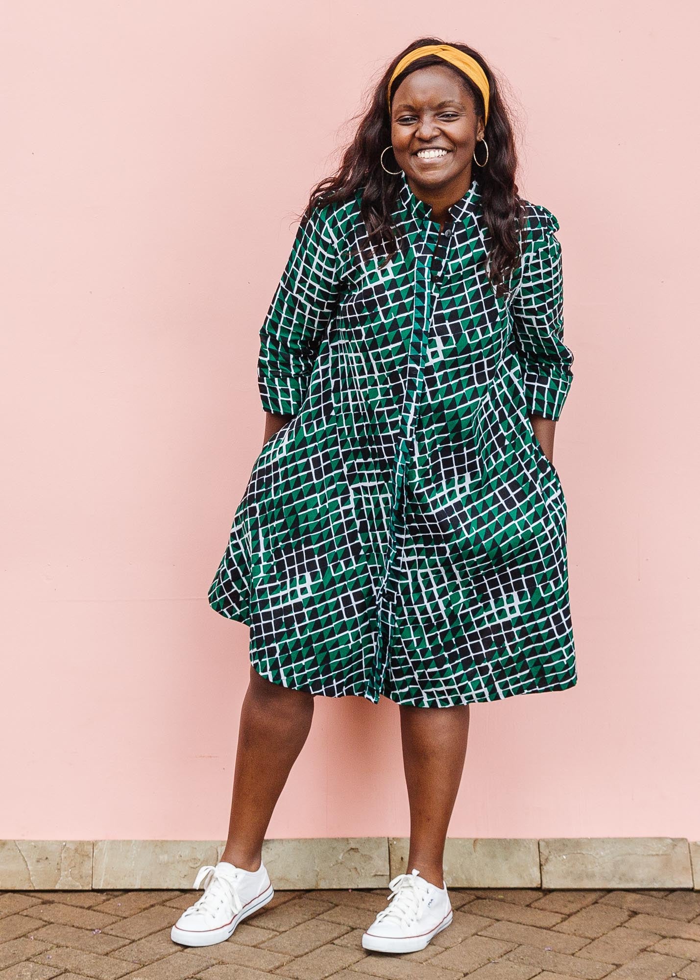 The model is wearing black, green and white geometric print dress