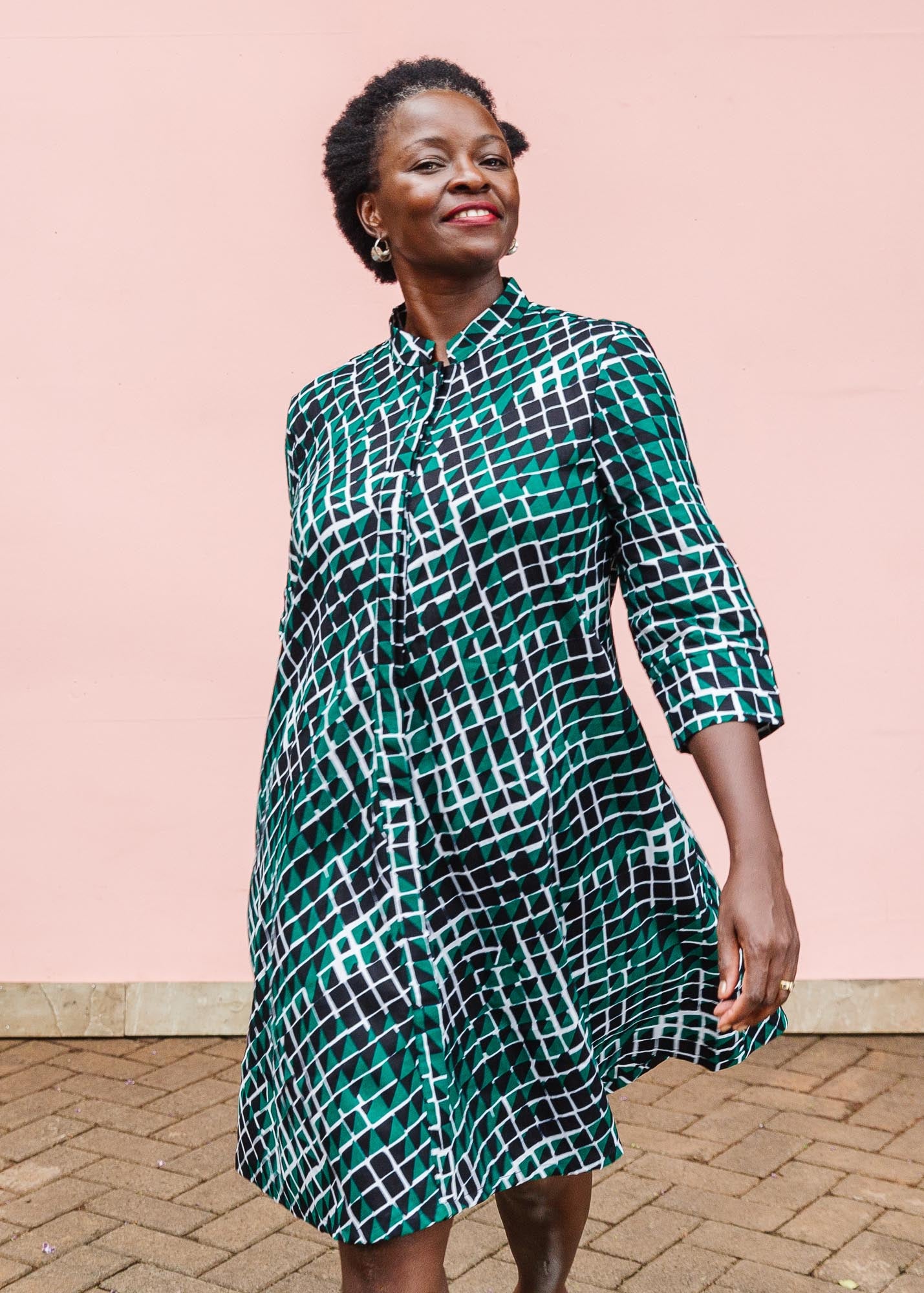 The model is wearing black, green and white geometric print dress