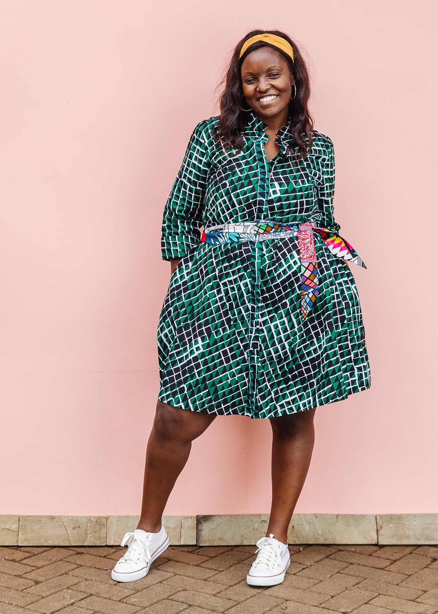 The model is wearing black, green and white geometric print dress