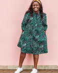 The model is wearing black, green and white geometric print dress