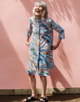 The model is wearing White, black, orange, blue, aqua and brown abstract print dress