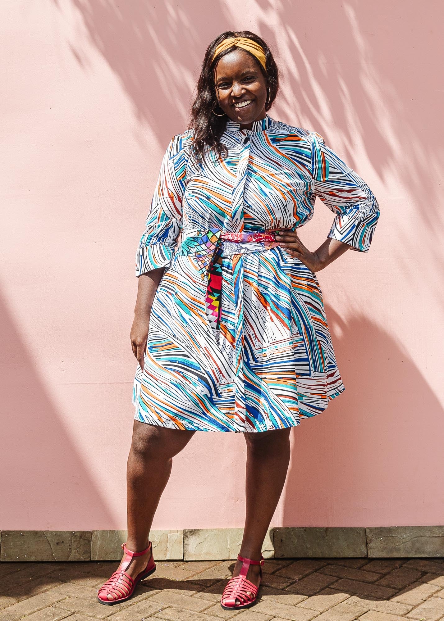 The model is wearing White, black, orange, blue, aqua and brown abstract print dress