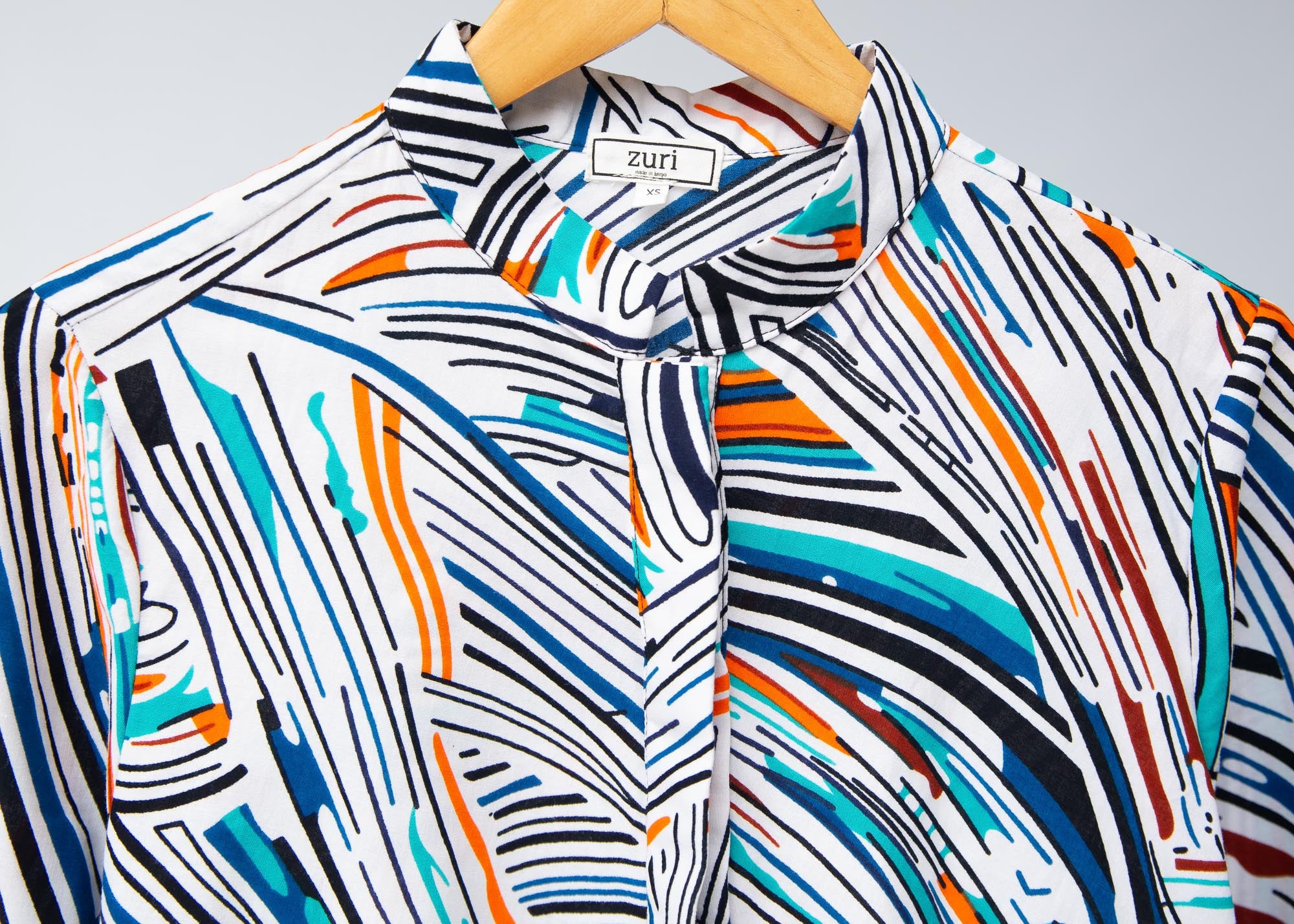 Display of white, black, orange, blue, aqua and brown abstract print dress